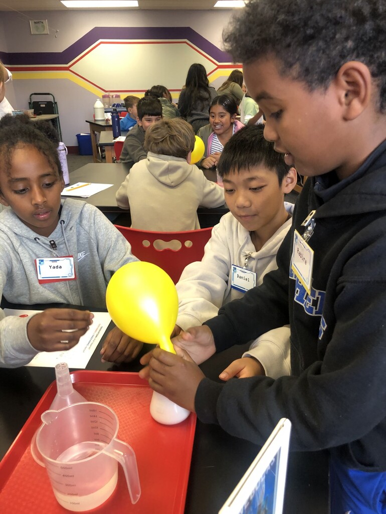three children work on a science experiment togetherYarely Chavez